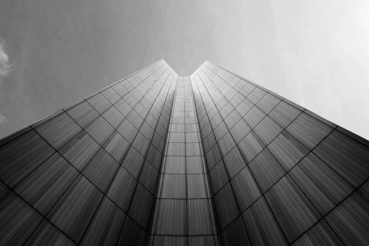 Twin glass towers converging against an overcast sky